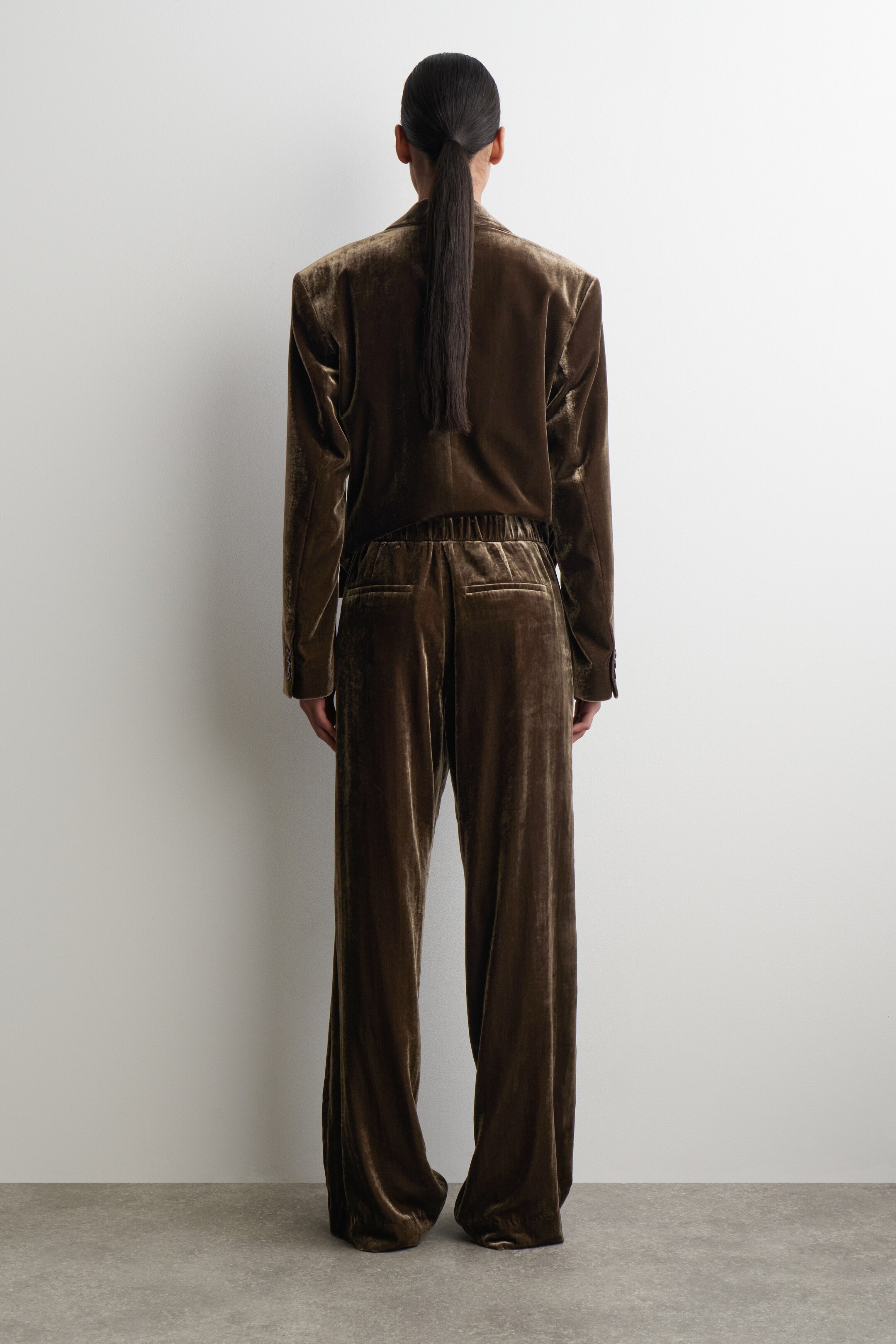 Agrandir l'image: Un costume en velours marron est présenté de dos, composé d'un blazer à manches longues avec des poignets boutonnés, et d'un pantalon à jambes larges avec une taille élastiquée.