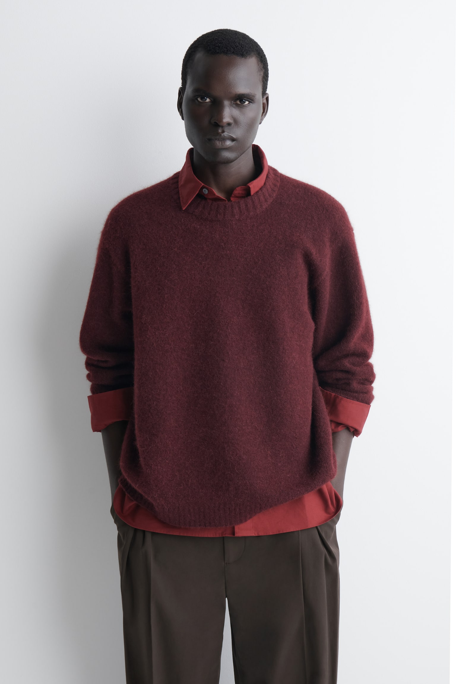 Un jersey oversize de mezcla de alpaca en un intenso tono burdeos presenta desde el frente una silueta relajada y holgada. La prenda presenta un tejido de punto afelpado y con textura, con cuello redondo acanalado, hombros caÃdos, puños acanalados y bajo acanalado. - 1