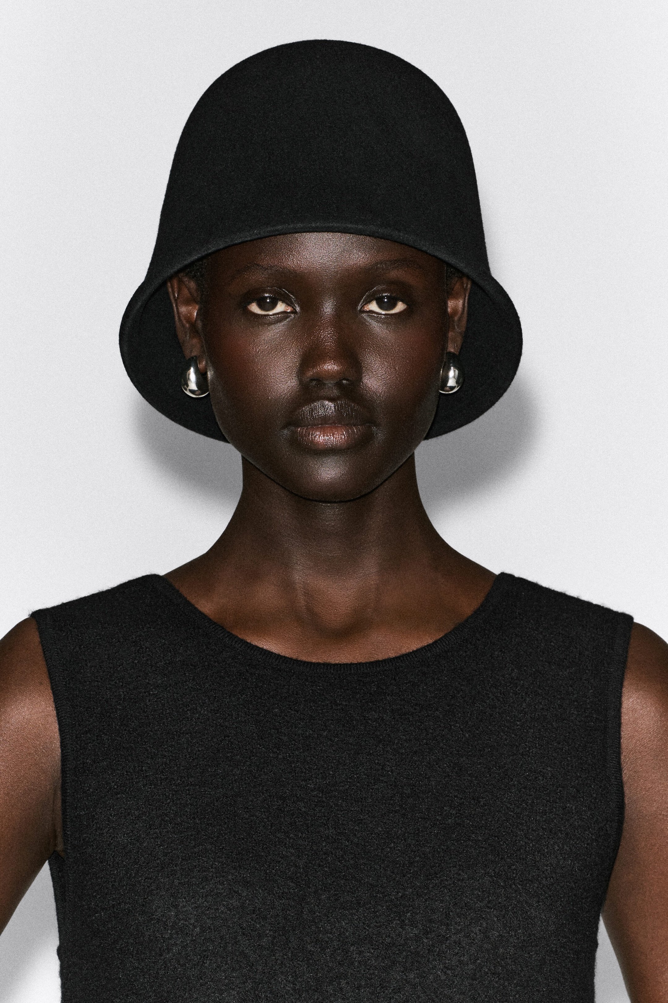 A black boiled wool bucket hat is shown from the front, featuring a softly sculpted, domed crown and a gently curved brim with a subtly folded edge. A black boiled wool bucket hat is shown from the front, featuring a softly sculpted, domed crown and a gently curved brim with a subtly folded edge.