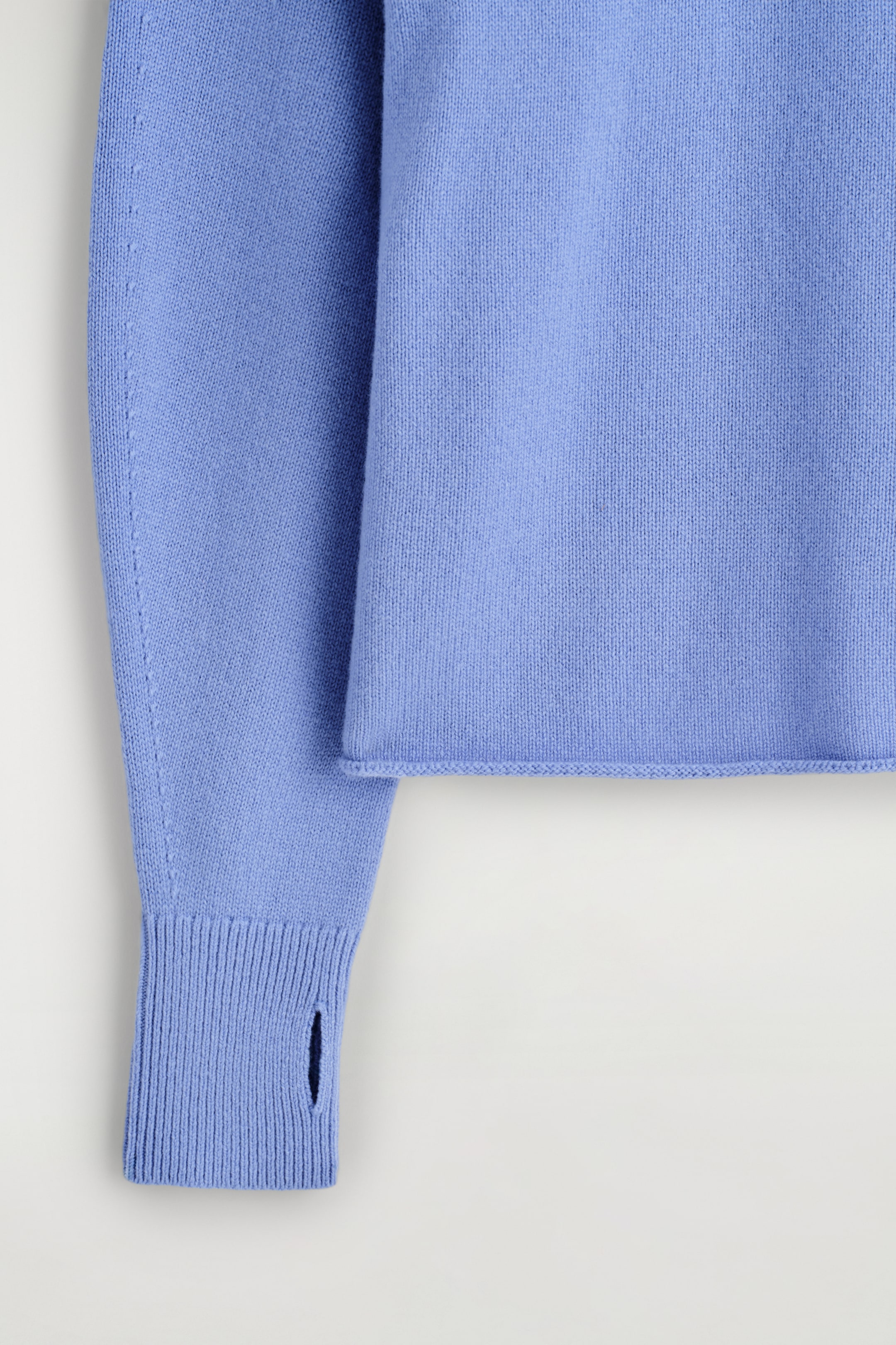 Visualizza immagine più grande: Un maglione a maglia fine di colore azzurro presenta un orlo pulito e una manica raglan con un dettaglio di cucitura visibile. La manica termina con un polsino a coste progettato con un'apertura per il pollice.