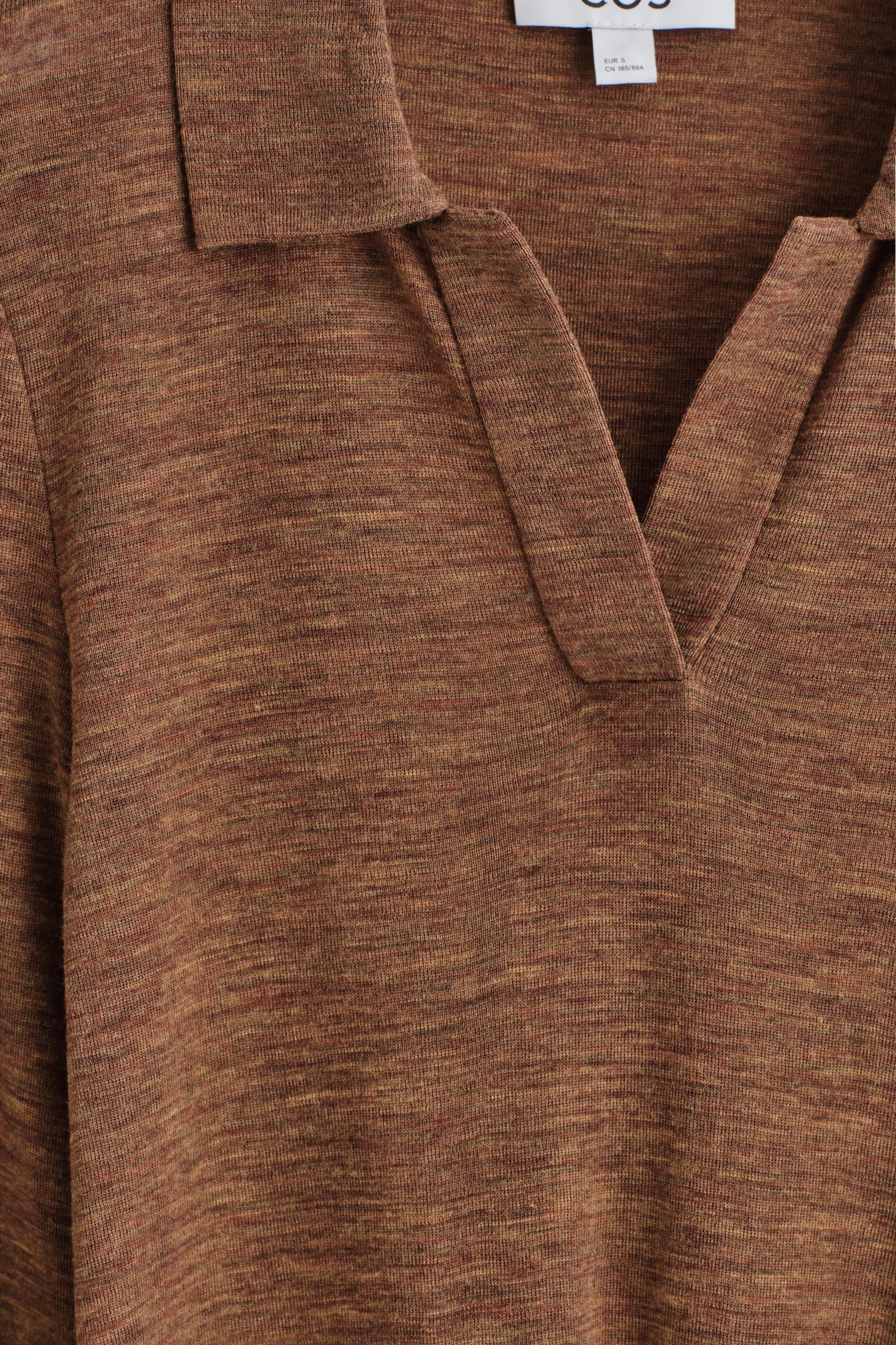 Visualizza immagine più grande: Un top polo finemente lavorato a maglia in un colore marrone screziato viene presentato FRONT, caratterizzato da un colletto a V aperto. Un'etichetta del marchio bianca è visibile sul retro del collo.
