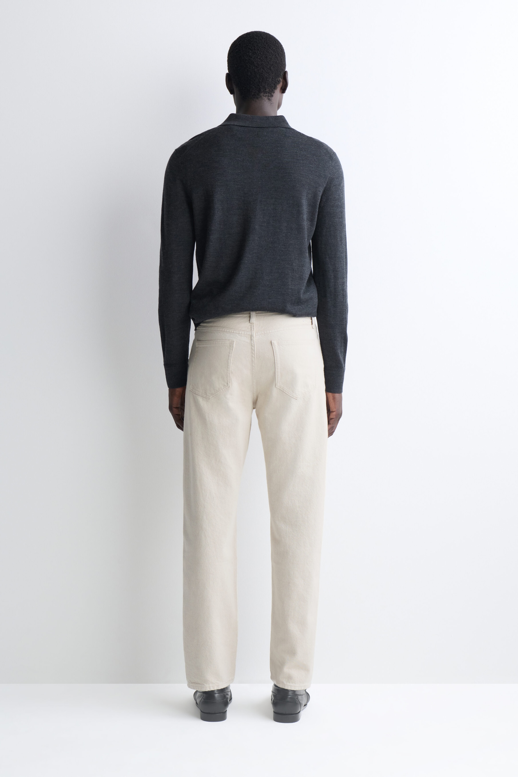 Ein langärmliges Strick-Poloshirt in Anthrazitgrau und gerade geschnittene Jeans in Off-White werden von hinten gezeigt, um ihre Struktur und Passform hervorzuheben. Das Poloshirt verfügt über einen klassischen Kragen und gerippte Ärmelbündchen, während die Jeans eine gerade Silhouette und zwei aufgesetzte Gesässtaschen aufweist. Ein langärmliges Strick-Poloshirt in Anthrazitgrau und gerade geschnittene Jeans in Off-White werden von hinten gezeigt, um ihre Struktur und Passform hervorzuheben. Das Poloshirt verfügt über einen klassischen Kragen und gerippte Ärmelbündchen, während die Jeans eine gerade Silhouette und zwei aufgesetzte Gesässtaschen aufweist.