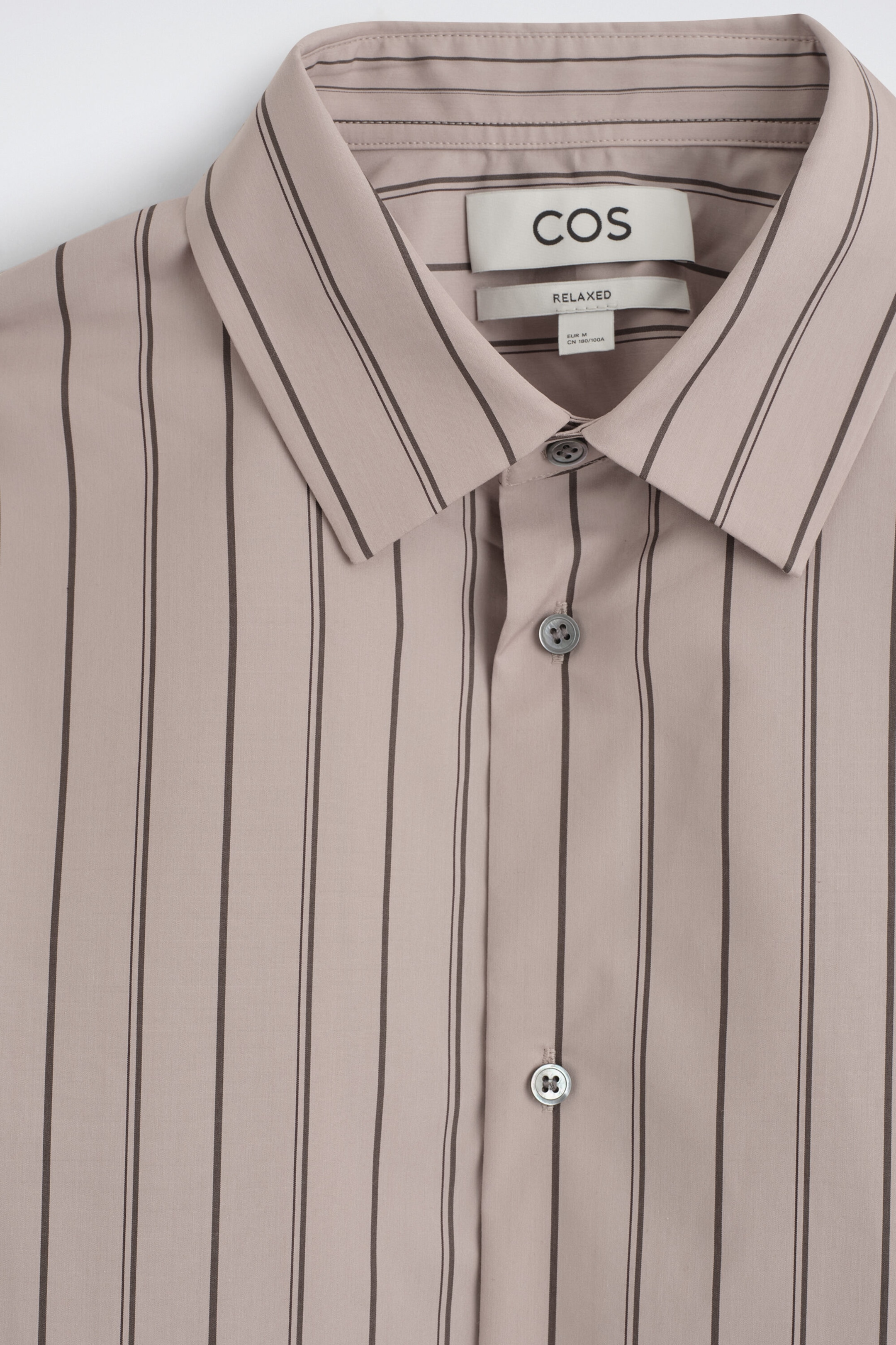 The striped structured cotton-silk shirt is shown in a close-up front view, showcasing its light taupe fabric patterned with thin dark vertical stripes. The shirt features a classic point collar, a buttoned front placket with grey buttons, and a brand label visible on the inside collar. The striped structured cotton-silk shirt is shown in a close-up front view, showcasing its light taupe fabric patterned with thin dark vertical stripes. The shirt features a classic point collar, a buttoned front placket with grey buttons, and a brand label visible on the inside collar.