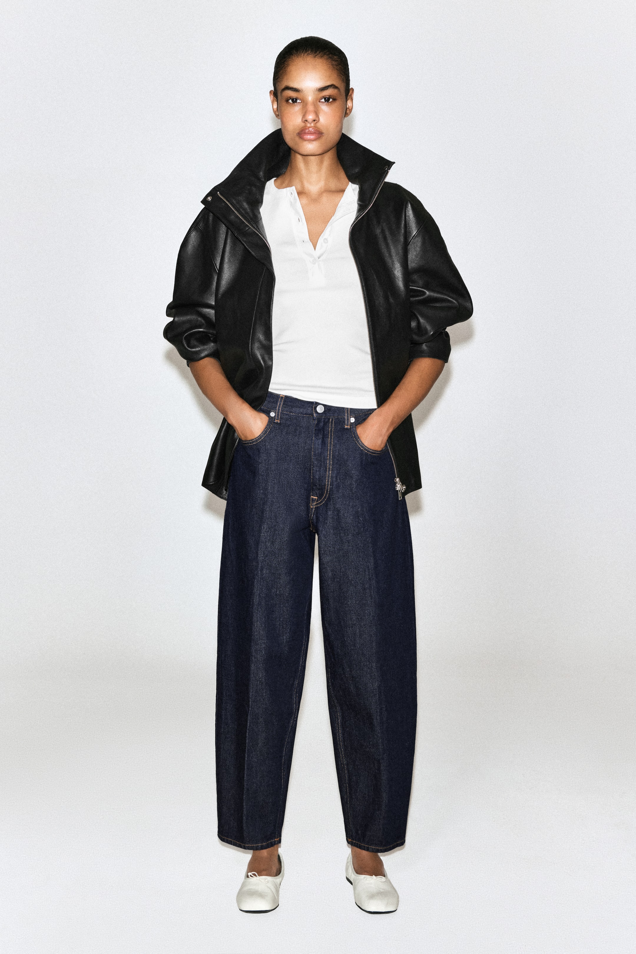 Größeres Bild ansehen: Die Umra Tapered Jeans präsentieren eine High-Rise-Silhouette mit weitem Bein, die zum Knöchel hin zuläuft und entlang der Mitte jedes Beins mit einer markanten vertikalen Bügelfalte versehen ist. Von vorne gezeigt, verfügen die dunkelindigofarbenen Denim-Jeans über kontrastierende goldene Nähte, ein klassisches Five-Pocket-Design und einen Bund mit Knopfverschluss, der durch ein eingestecktes Oberteil sichtbar wird.