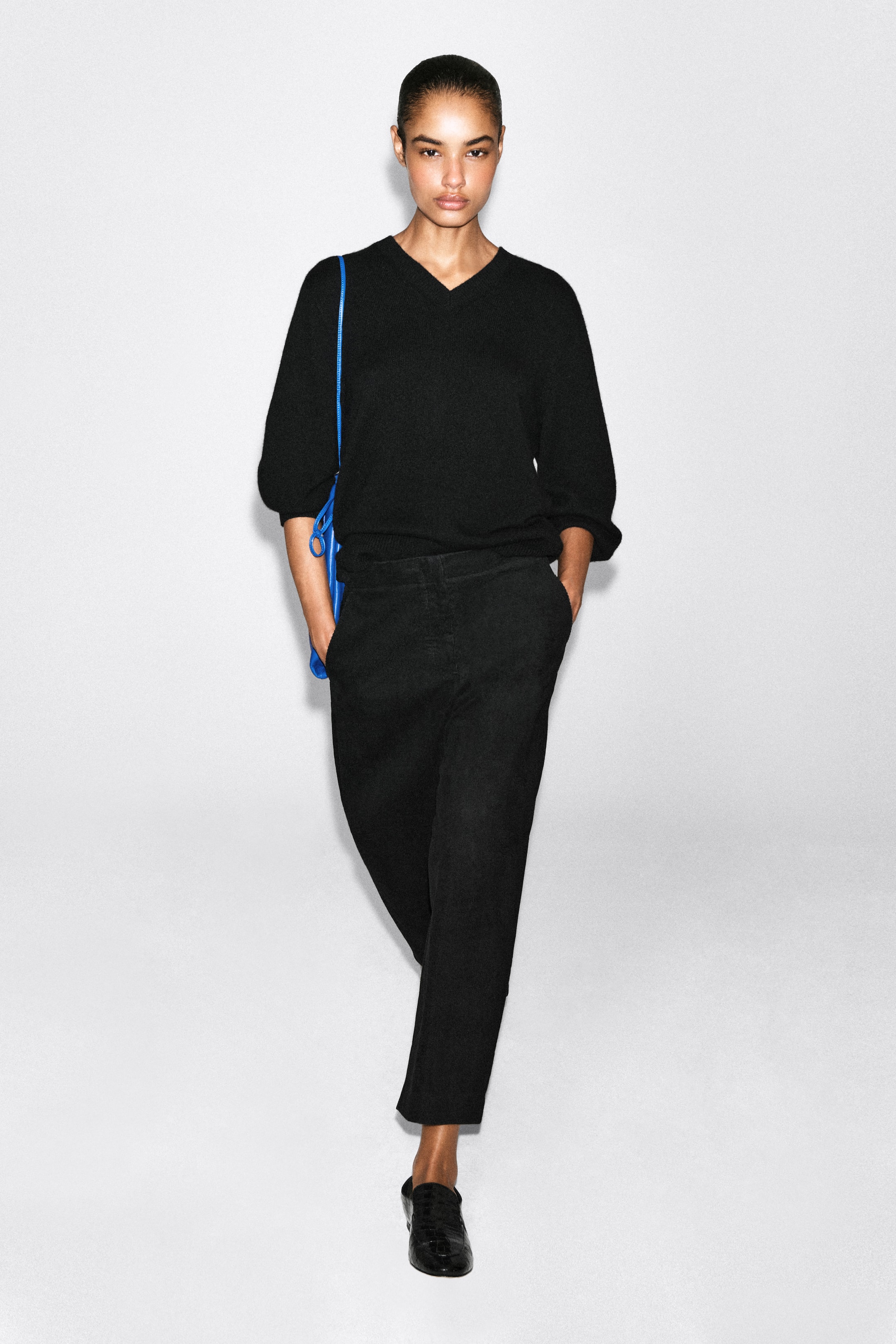 Ver imagen más grande: Estos pantalones barrel-leg de pana negra se muestran desde el frente, con una silueta curvada que se estrecha hacia el tobillo cropped. Los pantalones se combinan con un jersey de punto negro metido por dentro de la cinturilla, resaltando el tiro alto y los bolsillos laterales.