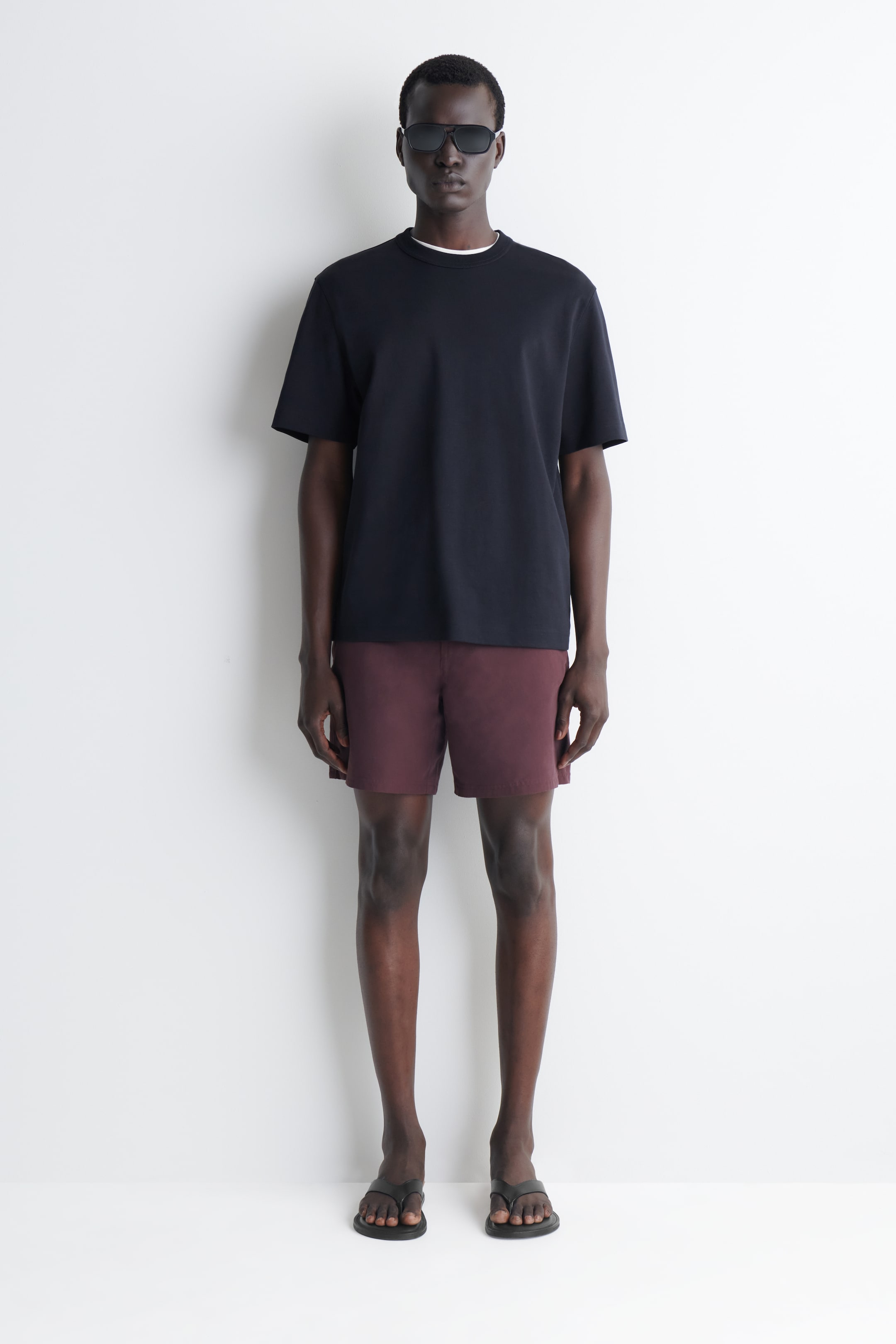 Visualizza immagine più grande: Una t-shirt girocollo blu scuro è presentata, caratterizzata da maniche corte e una vestibilità rilassata, con uno strato bianco visibile al collo.