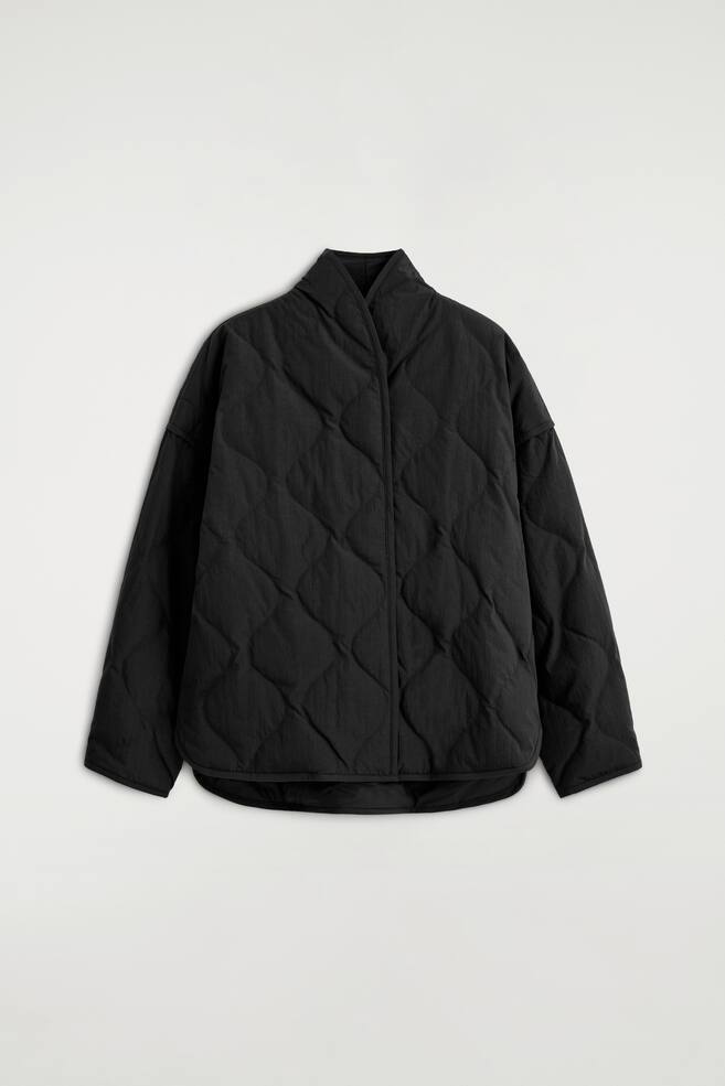 Die schwarze Steppjacke mit Schalkragen ist von vorne abgebildet und zeigt ein zwiebelfÃ¶rmiges Steppmuster sowie einen hohen, Ã¼berlappenden Schalkragen. Die Jacke hat Ã¼berschnittene Schultern, lange weite Ãrmel und einen geschwungenen Saum. - 1
