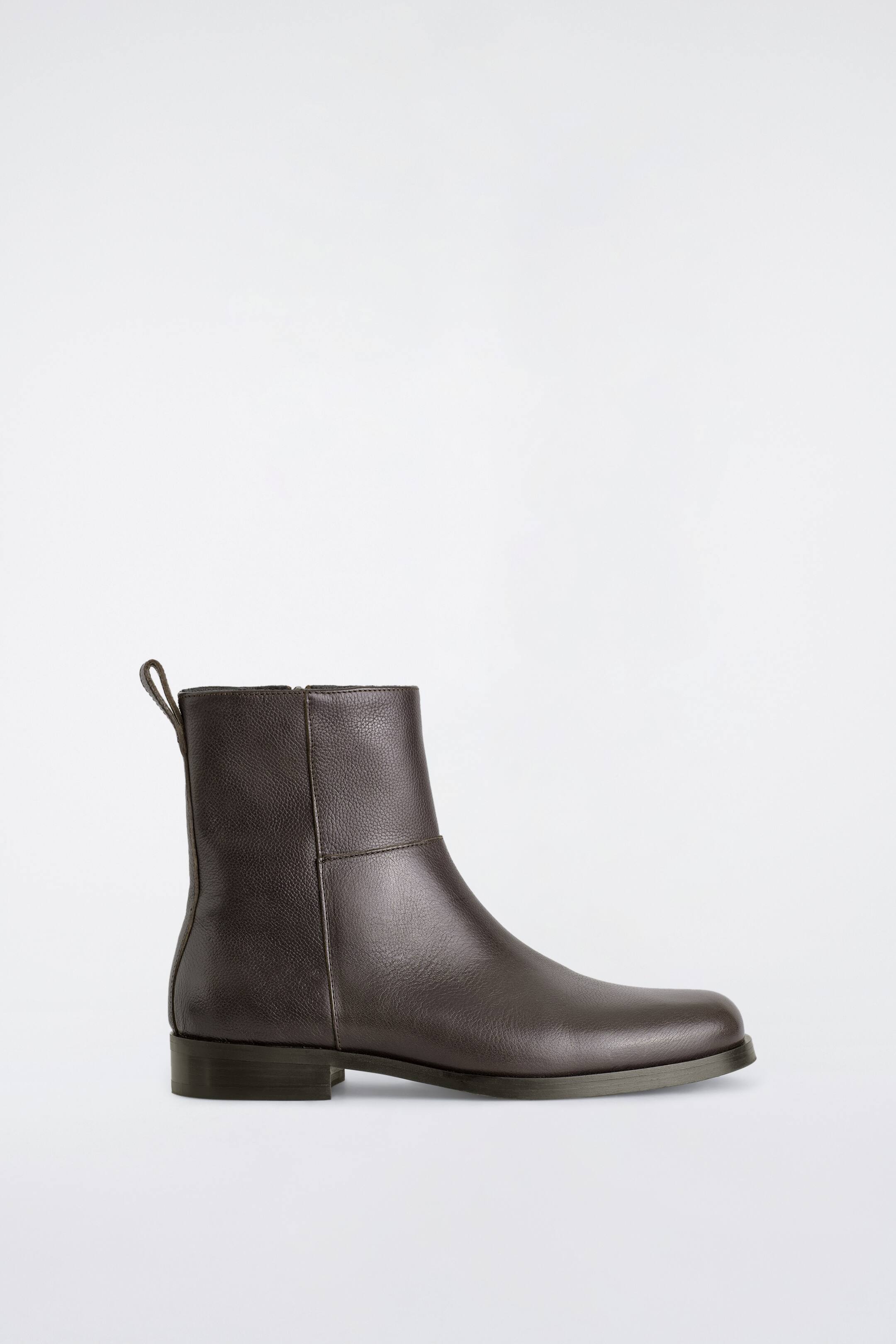 Grotere afbeelding bekijken: Leren enkelboots met vierkante neus in donkerbruin, naar rechts gericht in zijaanzicht, met een getextureerde, gekorrelde leren afwerking en een lage blokhak. De boot heeft een treklipje aan de achterkant van de kraag en gestikte naaddetails over de enkel schacht.