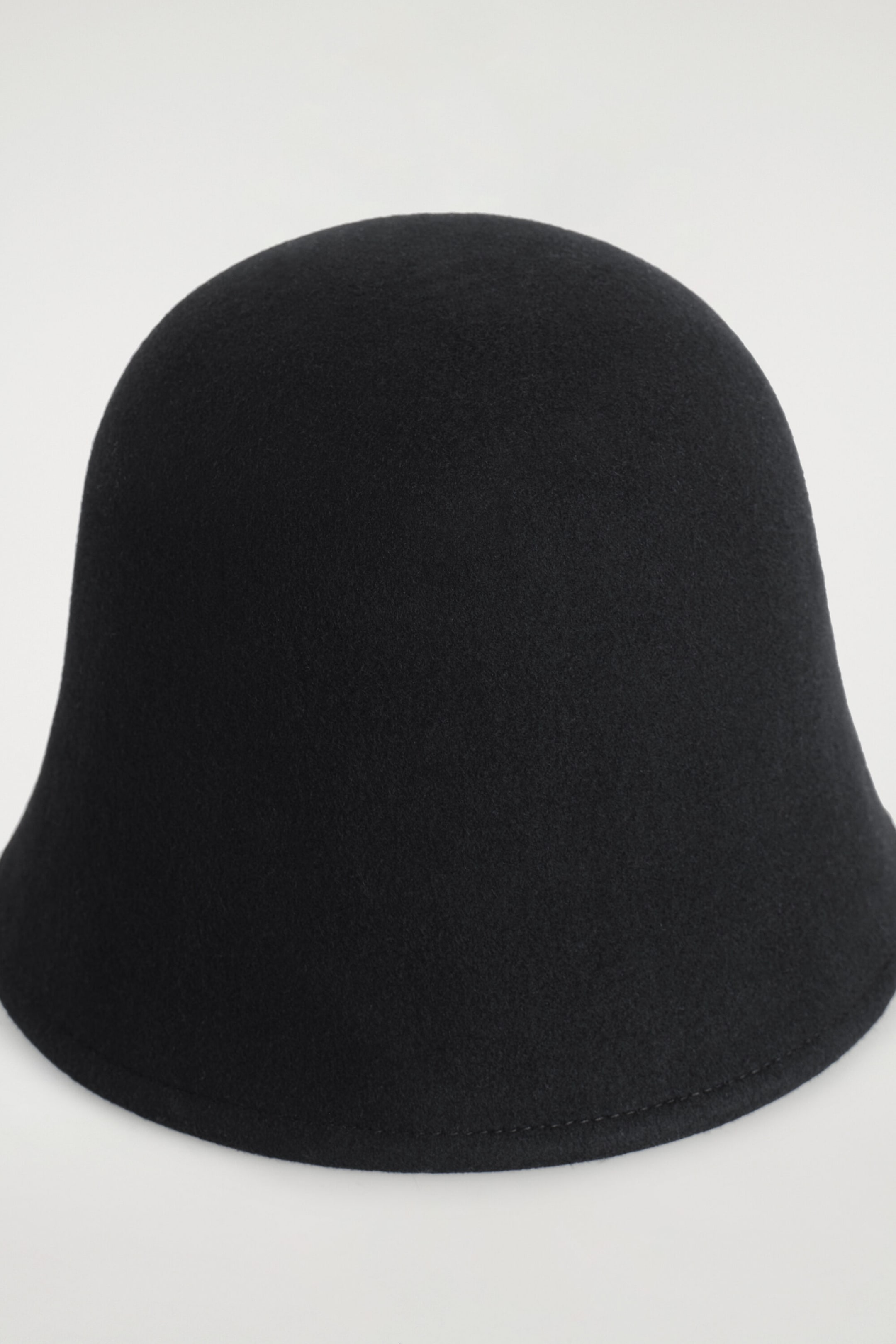 A black boiled wool bucket hat is shown from the front, featuring a structured, domed crown and a subtly flared brim with stitched detailing along the edge. A black boiled wool bucket hat is shown from the front, featuring a structured, domed crown and a subtly flared brim with stitched detailing along the edge.