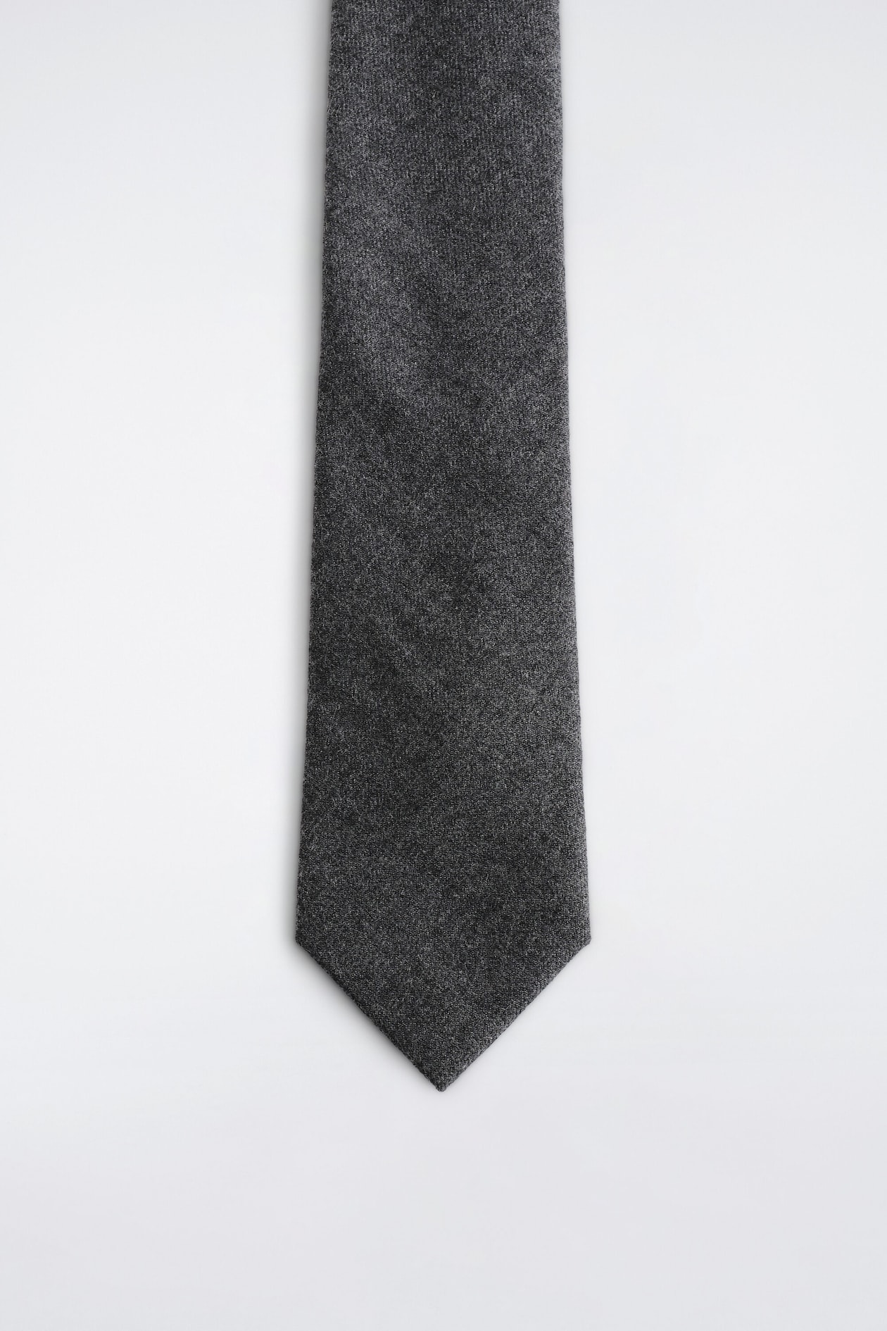 A dark grey textured tie is shown from the front, featuring a heathered matte fabric and a classic pointed tip.