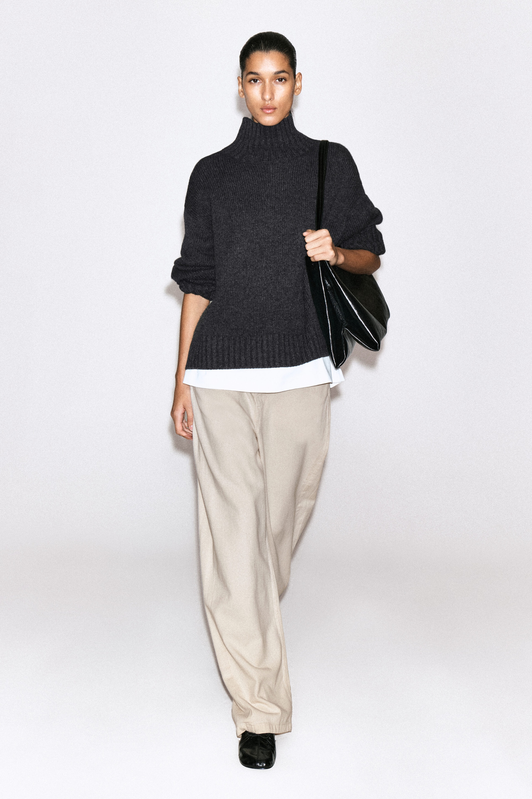 Lagoon wide-leg jeans in a light beige shade are shown from the front, featuring a relaxed wide-leg silhouette that drapes loosely over black shoes. The jeans are styled with a dark grey roll-neck jumper and a white shirt hem peeking out at the waist, highlighting their casual, slouchy fit. Lagoon wide-leg jeans in a light beige shade are shown from the front, featuring a relaxed wide-leg silhouette that drapes loosely over black shoes. The jeans are styled with a dark grey roll-neck jumper and a white shirt hem peeking out at the waist, highlighting their casual, slouchy fit.