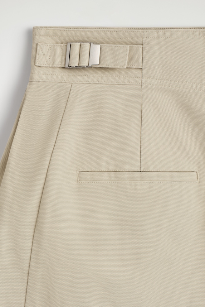 PLEATED BUCKLE-DETAIL MINI SKIRT — LIGHT BEIGE