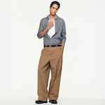 Placeholder for: Model wearing a checked shirt over a white tee, brown wide-leg trousers, and black shoes, posing with one hand in the pocket.