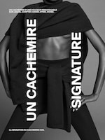 Placeholder for: A person wearing an elegantly draped cashmere garment, posed against a gray background, with text in French promoting signature cashmere.