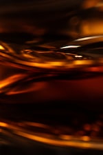 Placeholder for: Abstract close-up of swirling golden liquid with reflections and highlights, creating a warm and dynamic visual effect.
