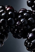 Placeholder for: Close-up of shiny, dark blackberries with a glossy finish, against a dark background.