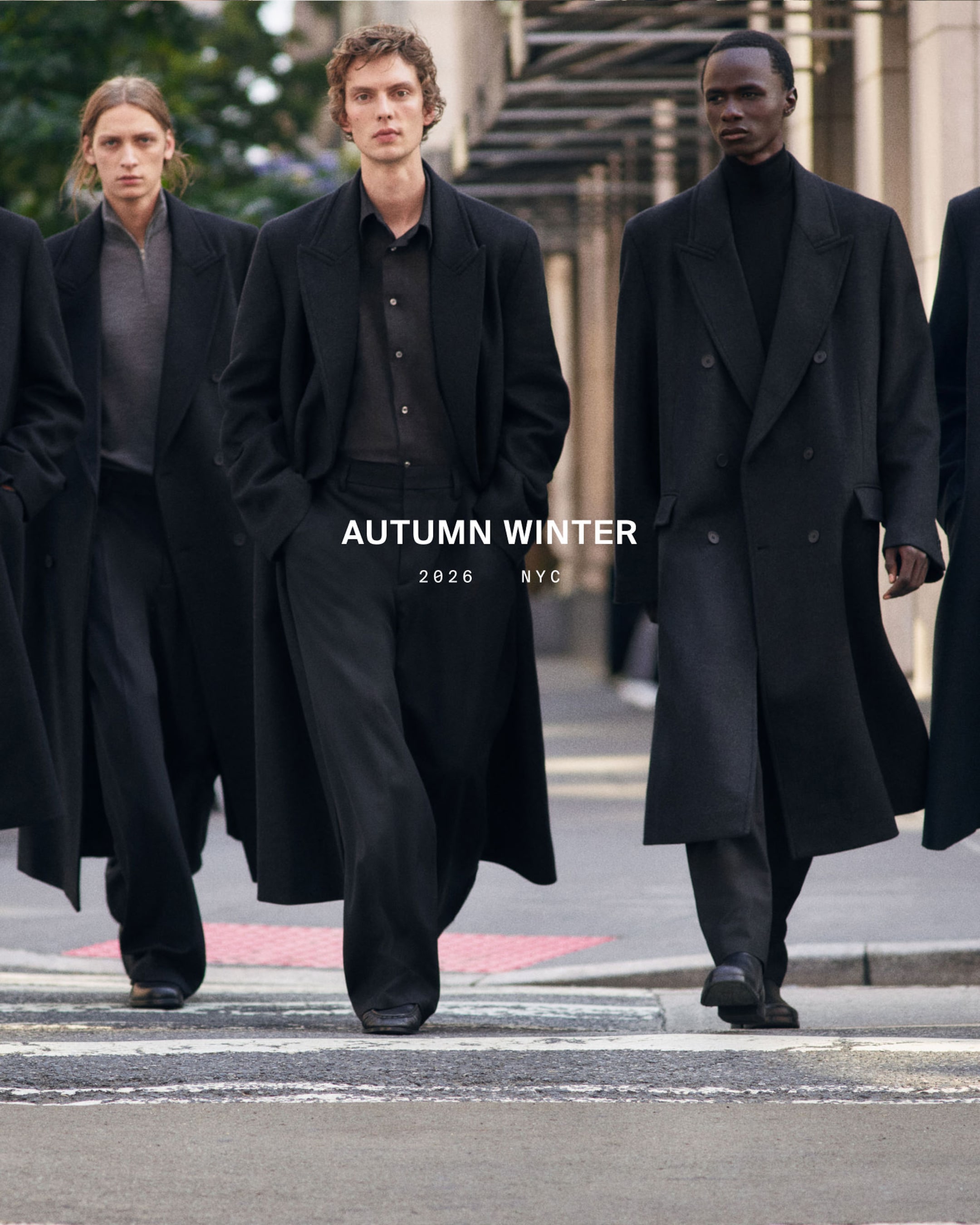 Three models in long dark coats walk confidently on a city street. Text reads "HERBST/WINTER 2026 NYC."