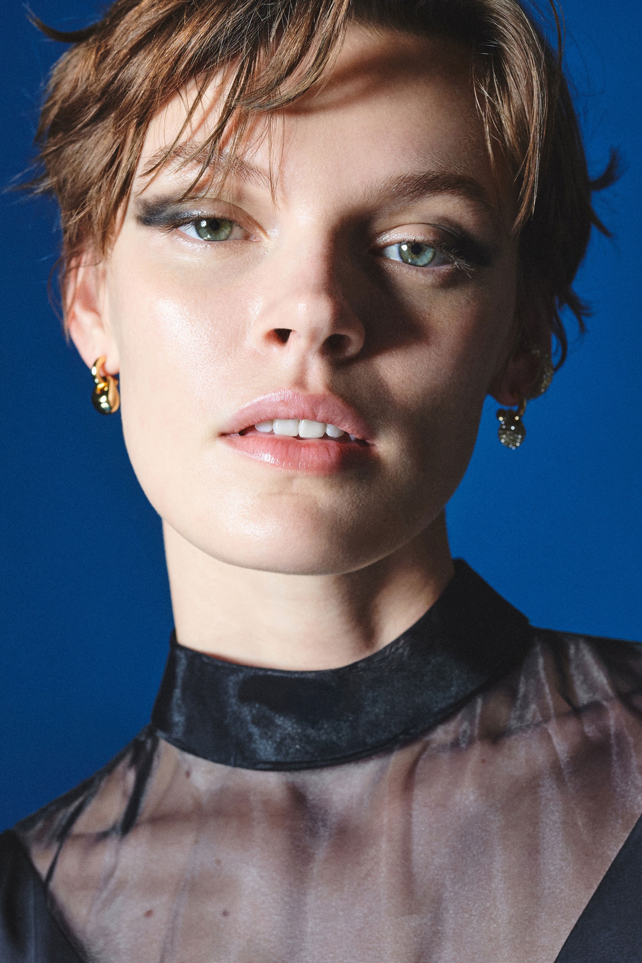 Woman wearing gold earrings and sheer top