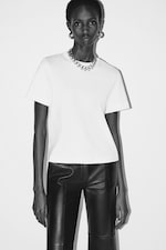 Placeholder for: Black and white image of woman wearing white top and gold chain necklace