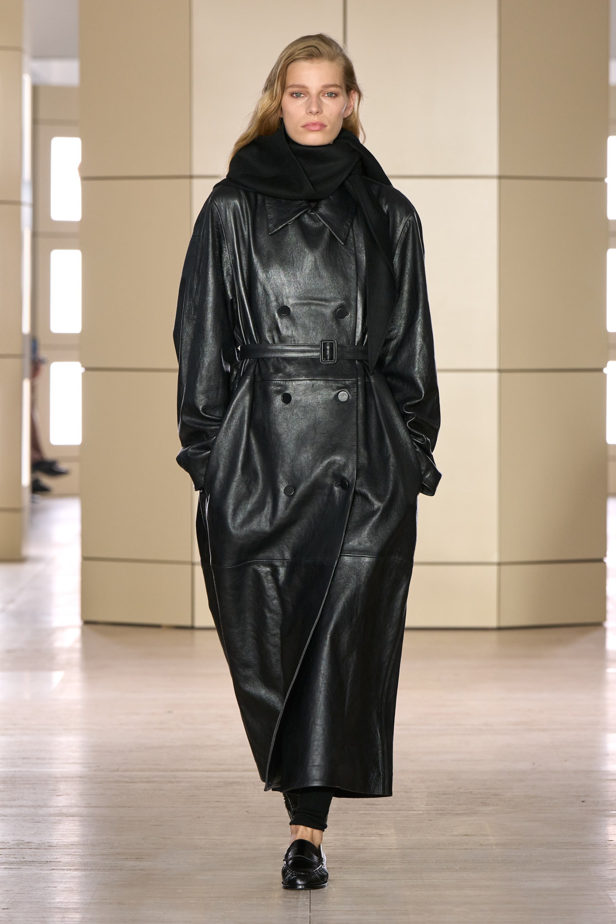 Person walking on a runway wearing a black leather coat