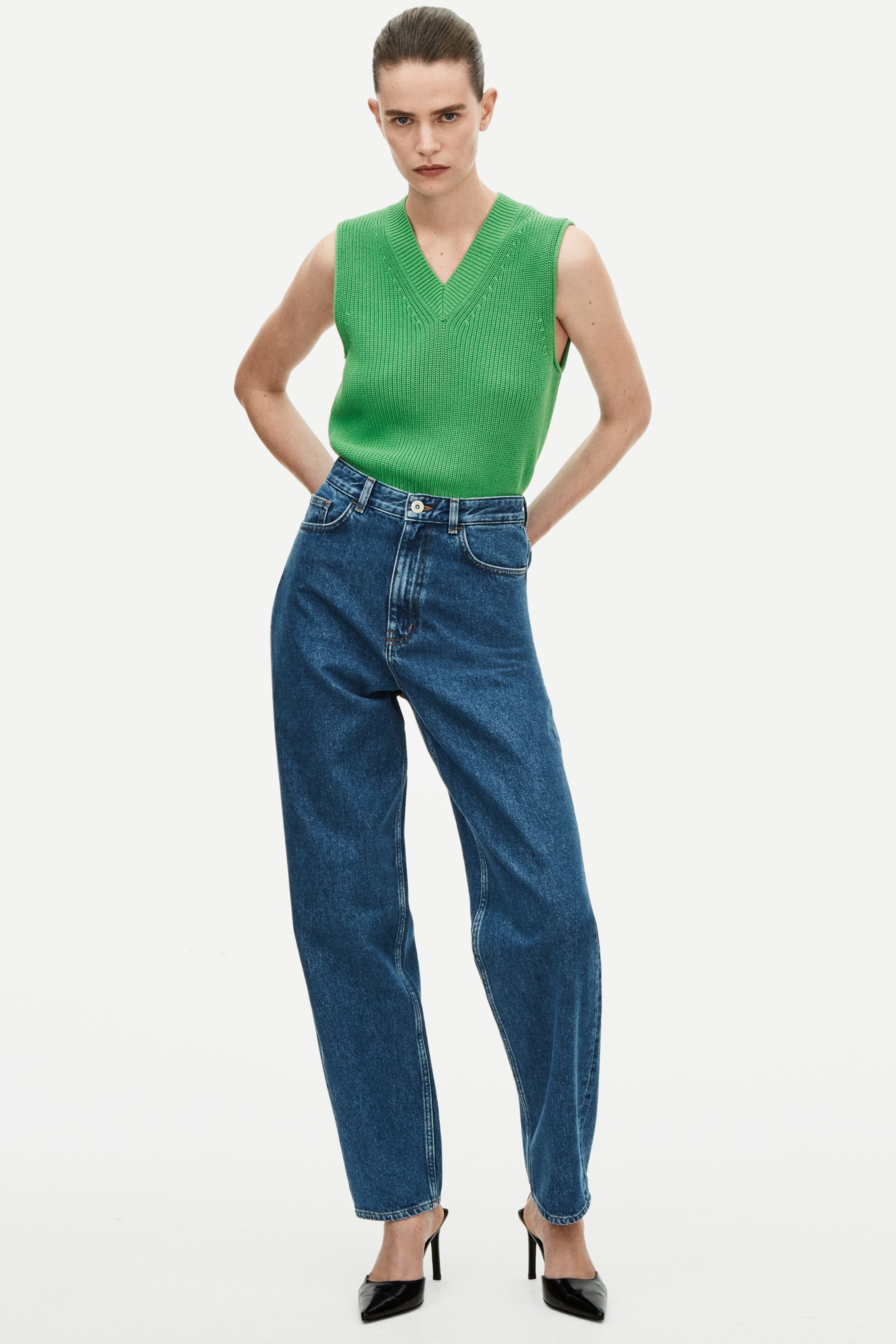 Woman wearing green knitted vest and blue jeans