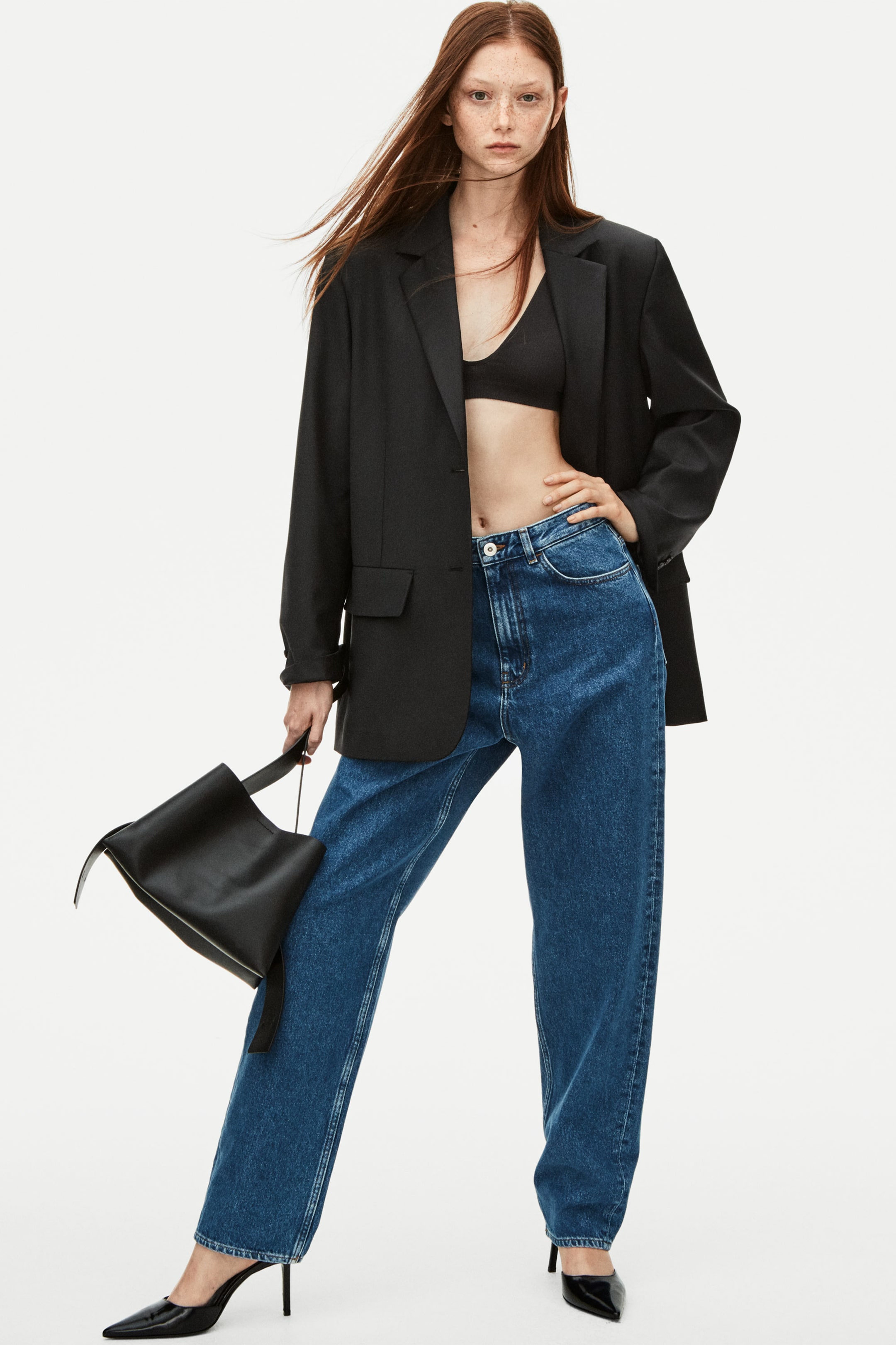 Woman wearing black blazer, bralette and blue jeans