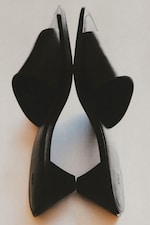 Placeholder for: Two black high-heeled shoes placed sole-to-sole on a light background, creating a symmetrical, artistic composition.