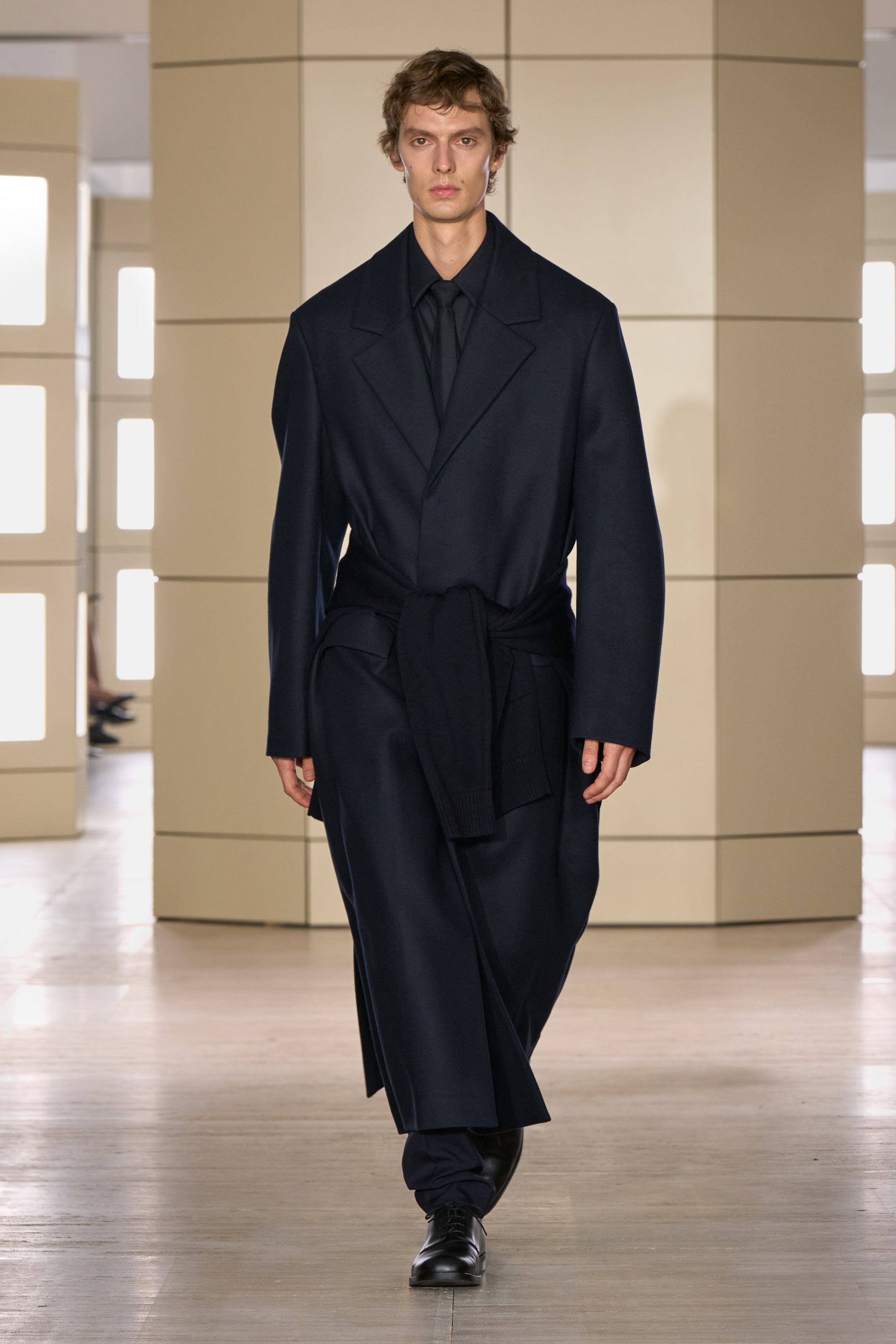Person walking on a runway wearing a dark coat