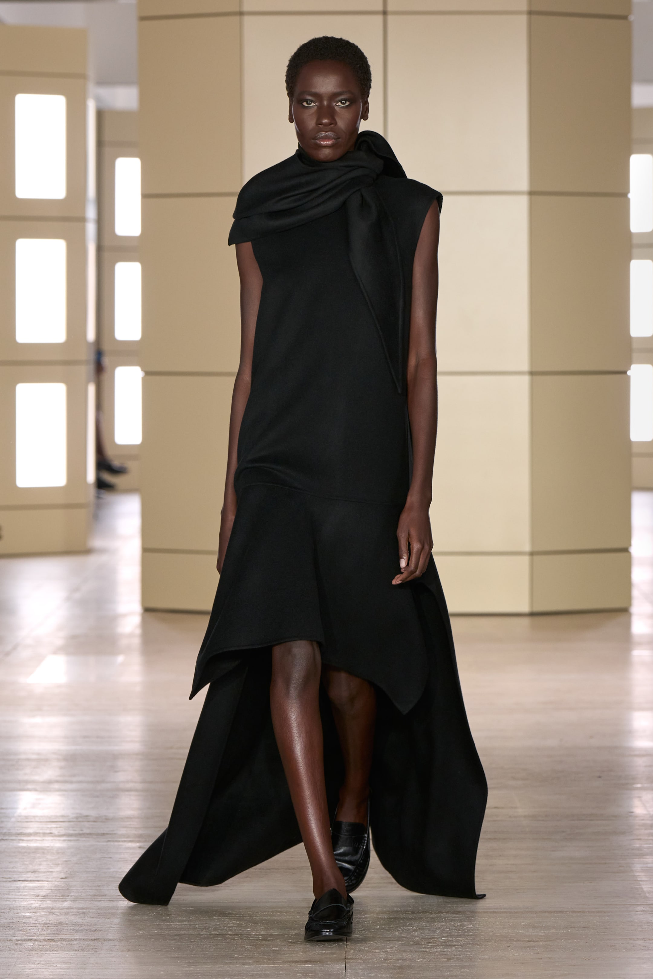 Person walking on a runway wearing a black dress