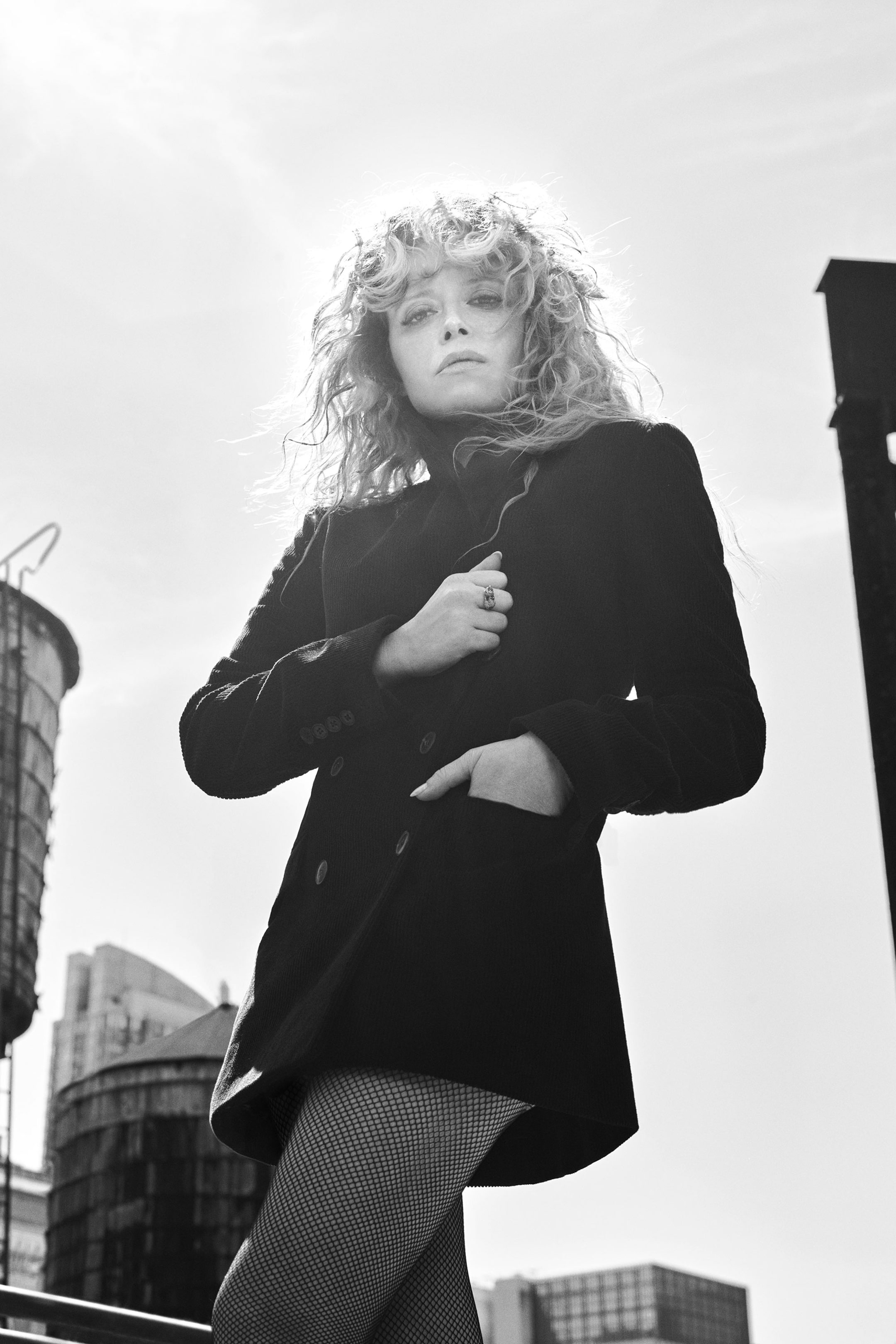 Natasha Lyonne wearing black buttoned coat and fishnet tights