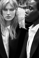 Placeholder for: Two people in black and white, wearing suits and white shirts. One has long hair; the other has short hair. The setting appears urban.
