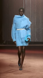 Placeholder for: Woman wears blue knitted dress, blue scarf and carries blue bag