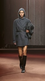 Placeholder for: Woman wears grey coat, grey hooded top and carries black bag