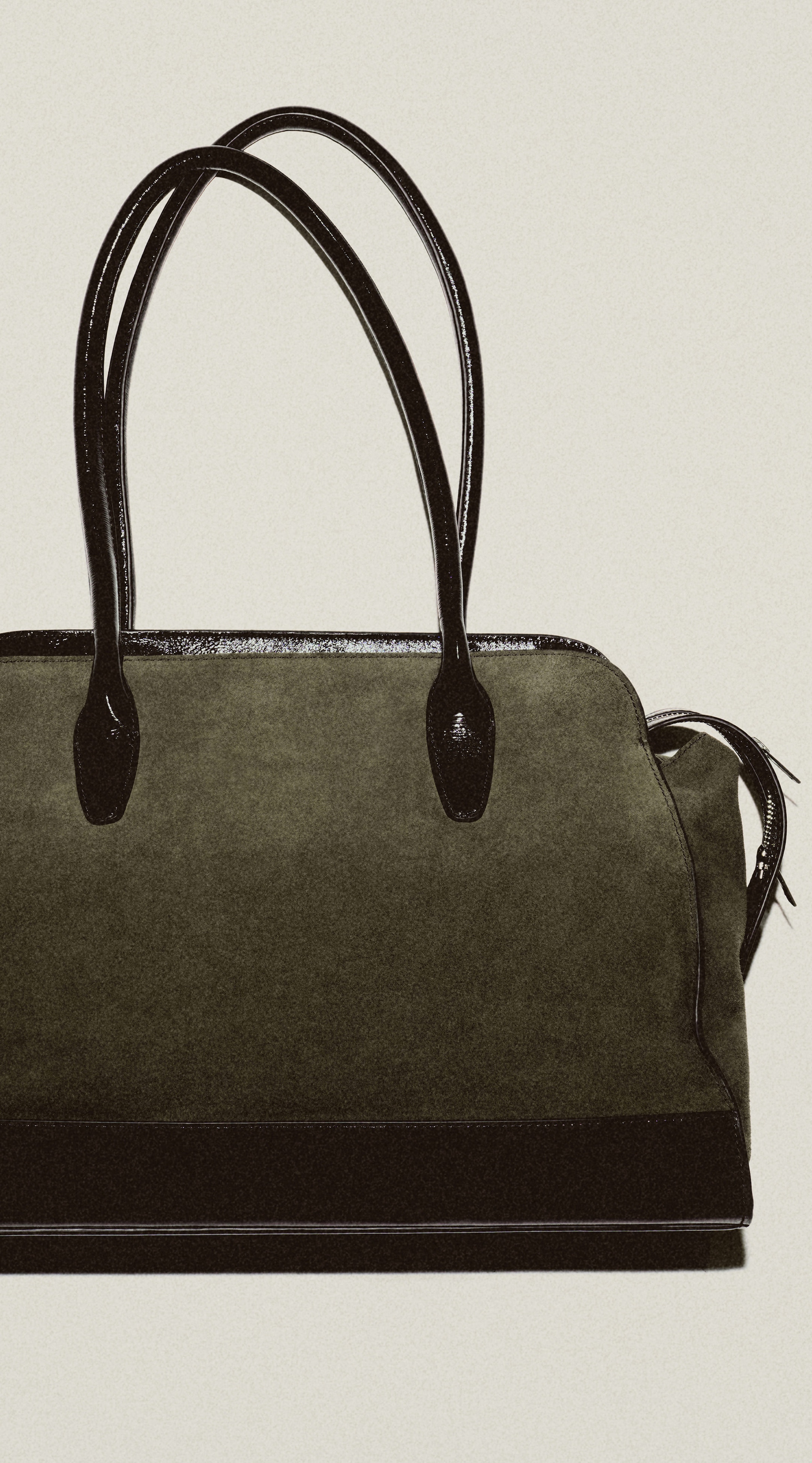 A stylish black handbag with sleek leather handles and accents, set against a plain background.