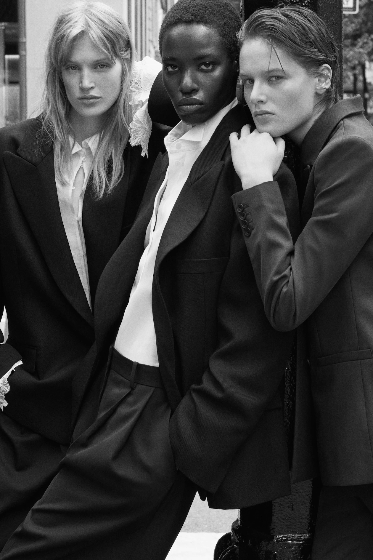 Three individuals in suits pose confidently in a black-and-white photograph, exuding style and sophistication.