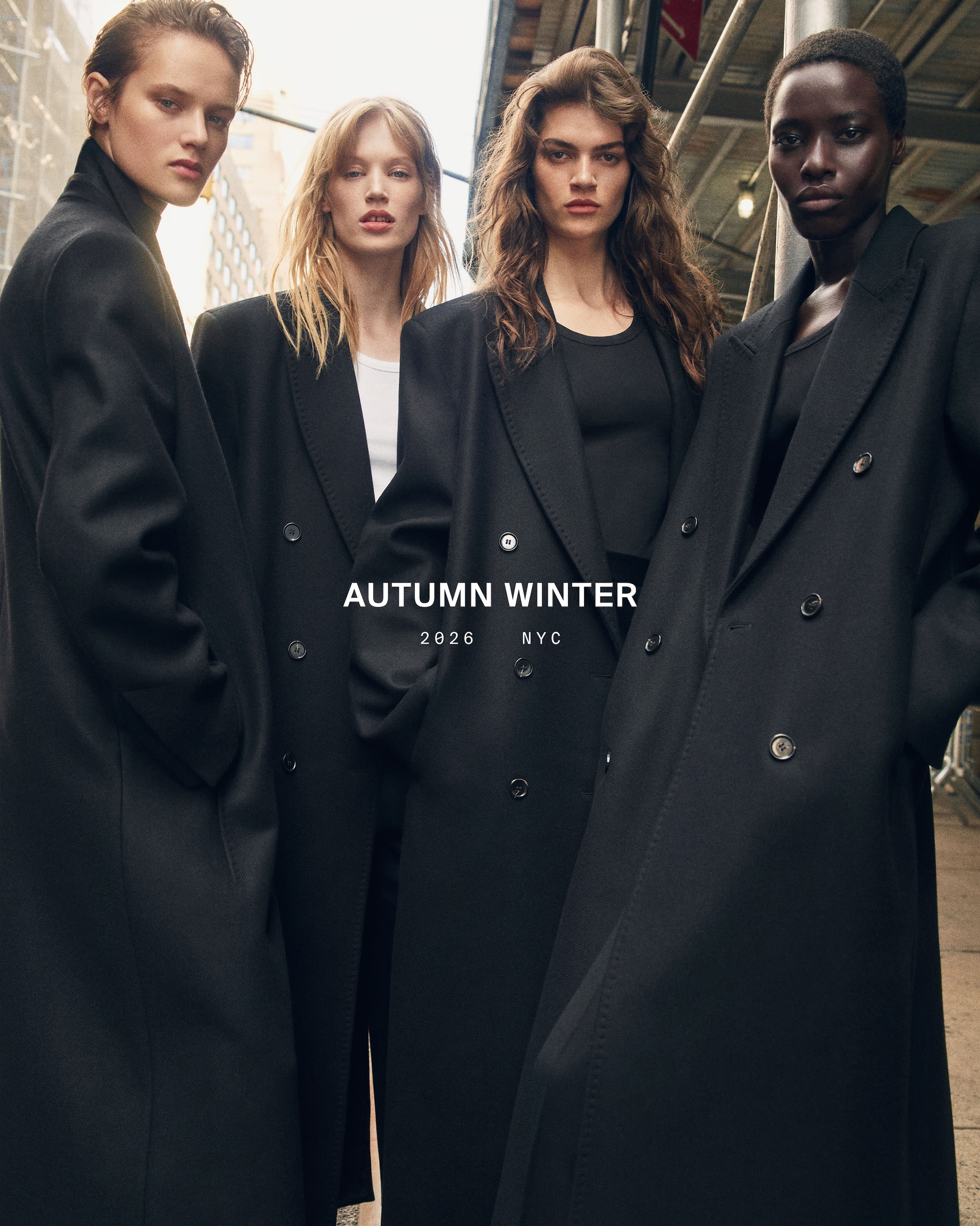 Four models in long black coats pose in an urban setting, promoting an Autumn Winter 2026 fashion collection in NYC.