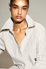Placeholder for: Person wearing a striped, open-collar shirt, looking directly at the camera, with a neutral expression.
