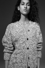 Placeholder for: Black-and-white portrait of a woman with long curly hair wearing a chunky marled button-up cardigan, neutral expression.