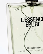 Placeholder for: Close-up of a perfume bottle labeled "L'Essence Epure" by COS Perfumery, showing clear liquid with air bubbles inside.
