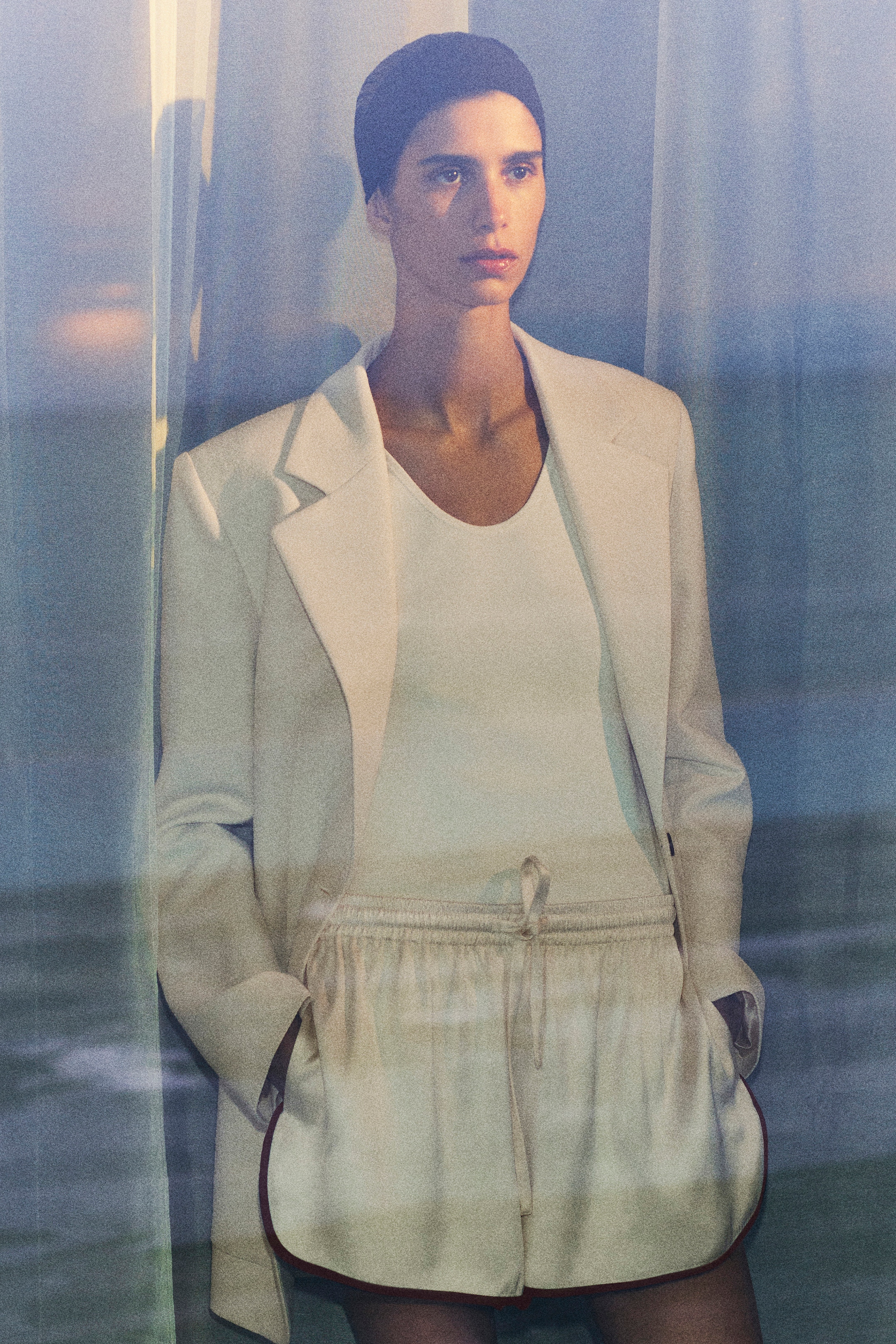 woman in beige blazer, white top and cream satin shorts