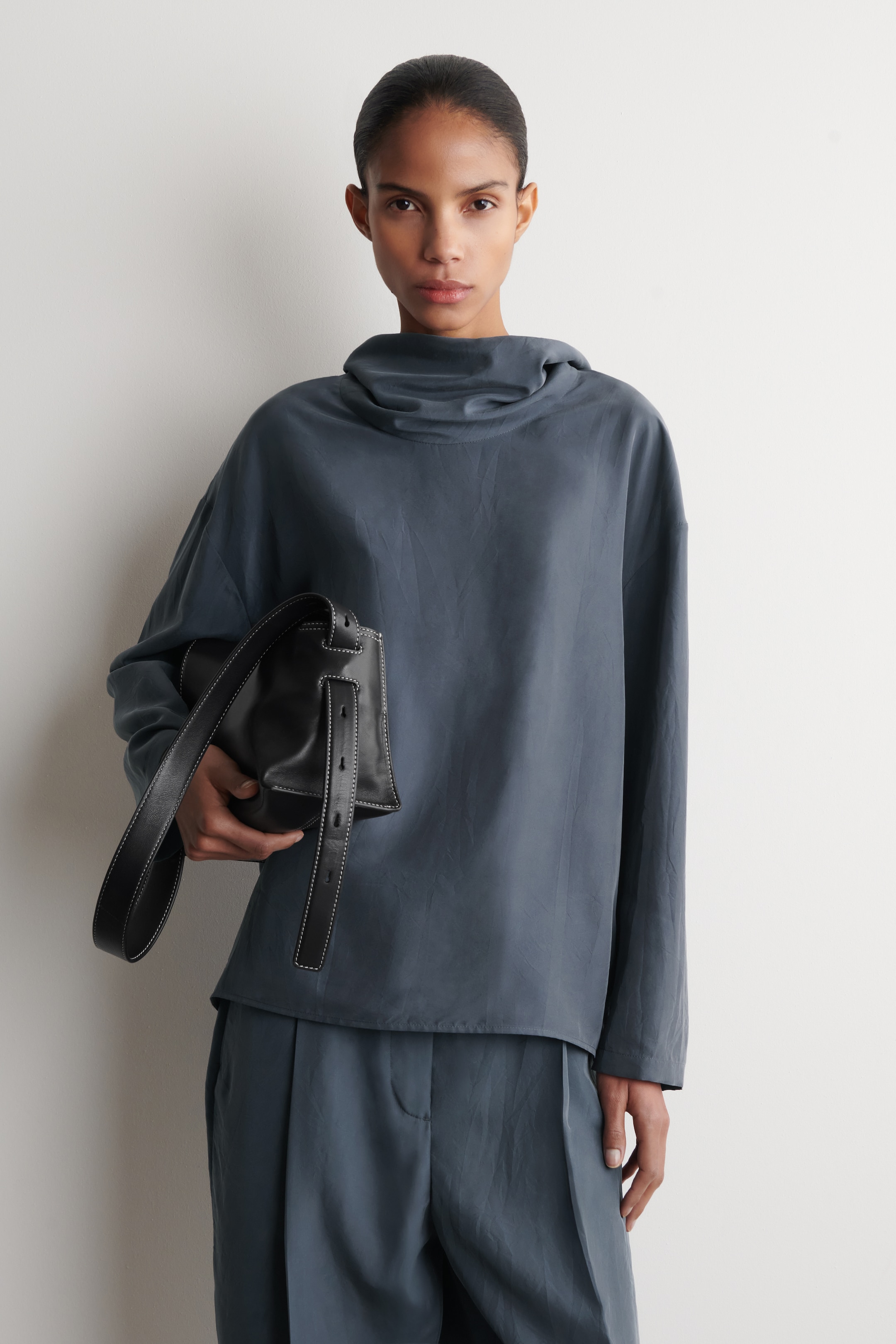 woman in navy silk funnel top with bag