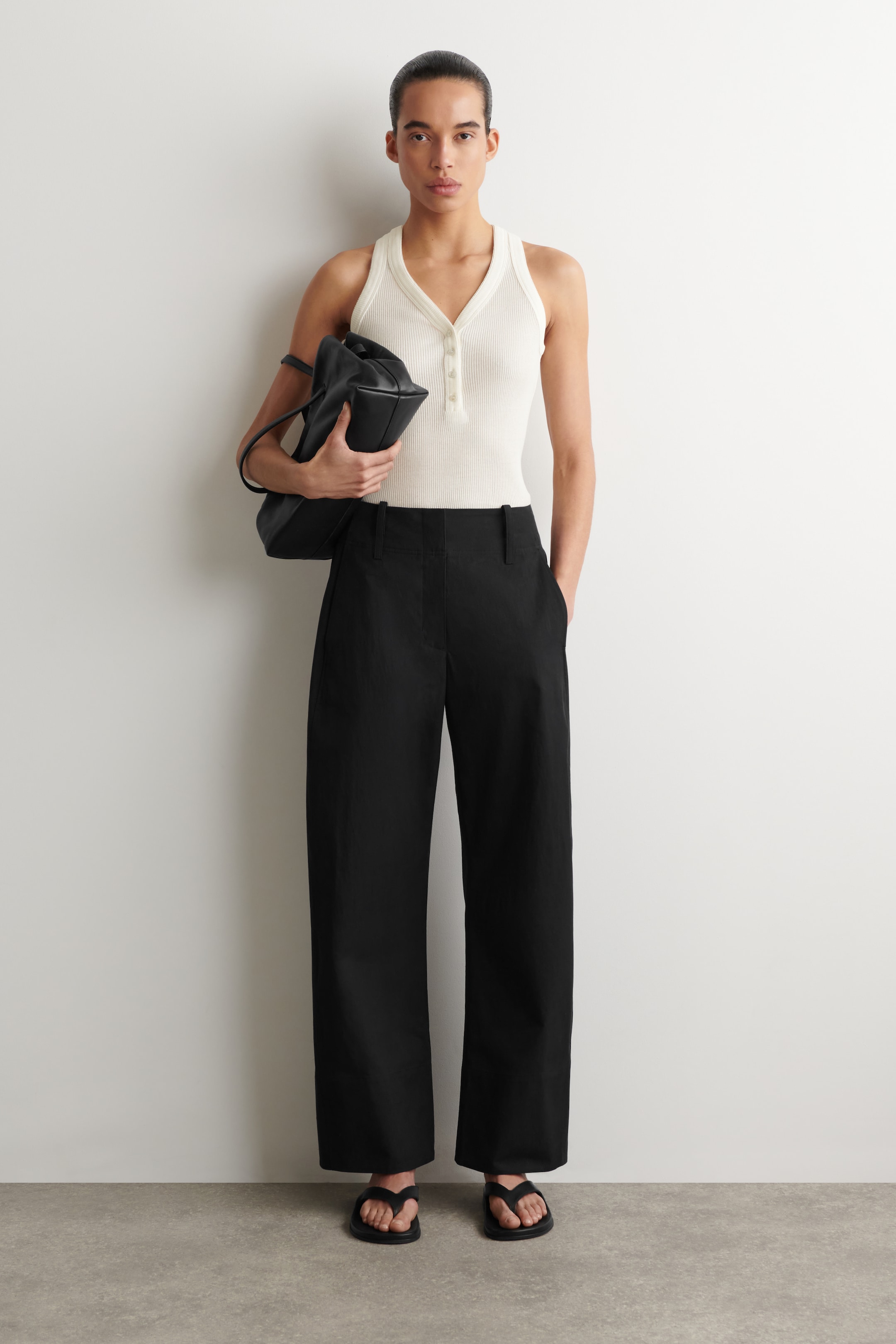 woman in white knitted top and black trousers