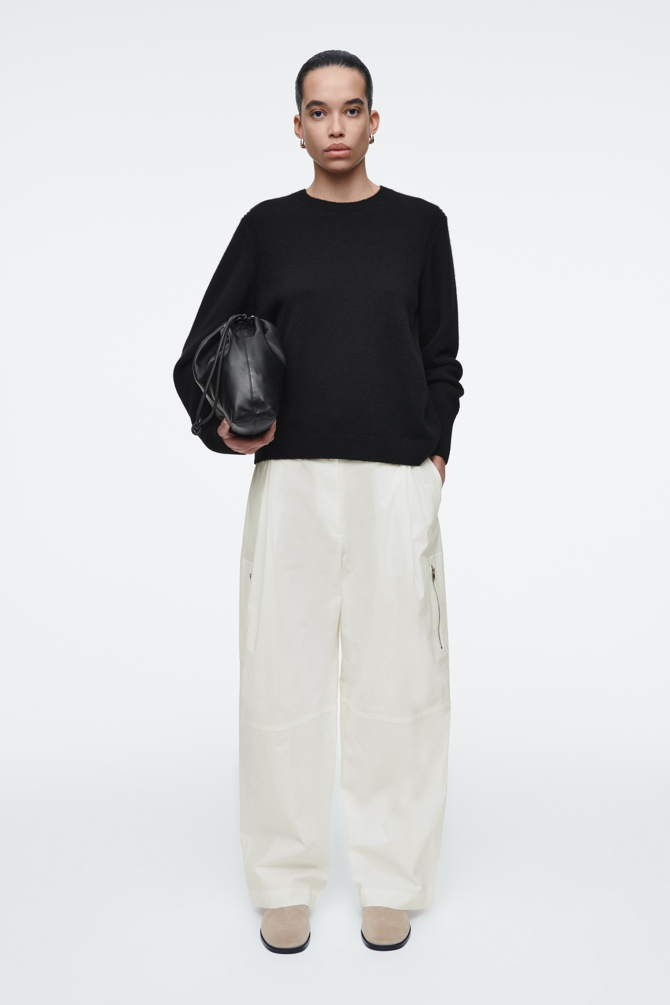 Person wearing black top and white trousers
