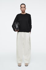 Placeholder for: Person wearing black top and white trousers
