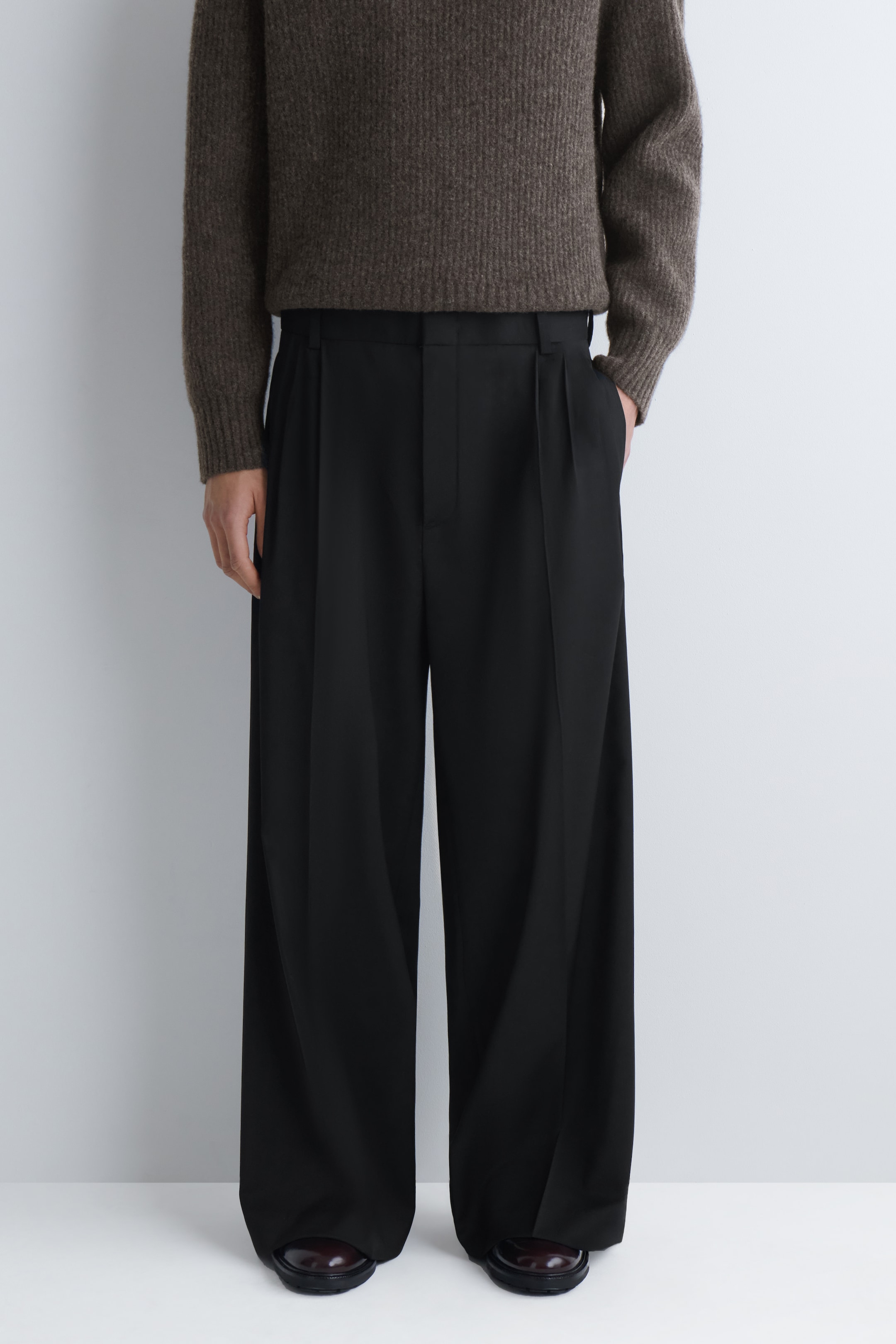 man in wide leg black trousers with pleats