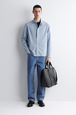 Placeholder for: model wearing a light blue shirt over a black t-shirt with mid wash denim