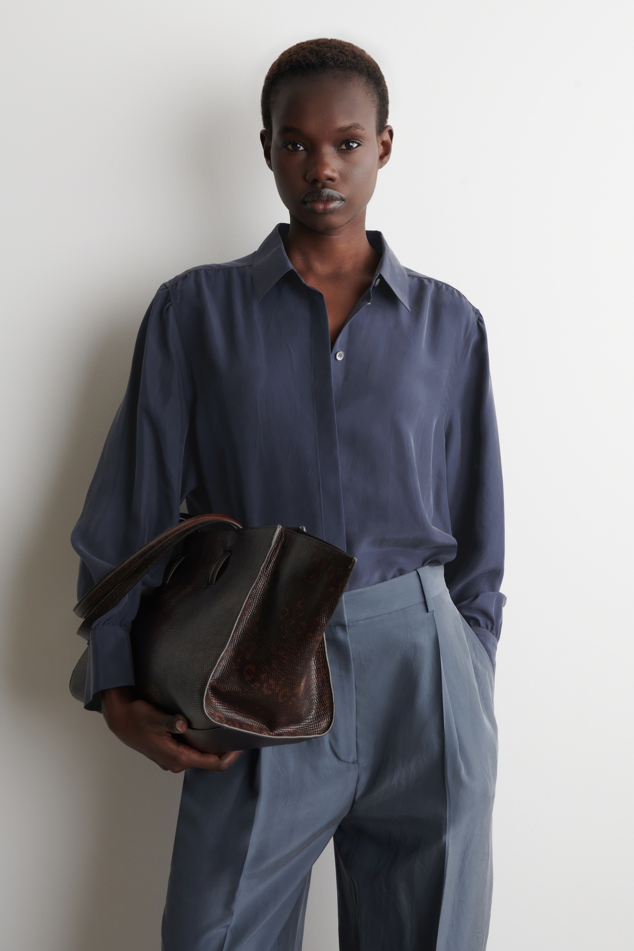 woman in navy silk shirt and trousers with bag