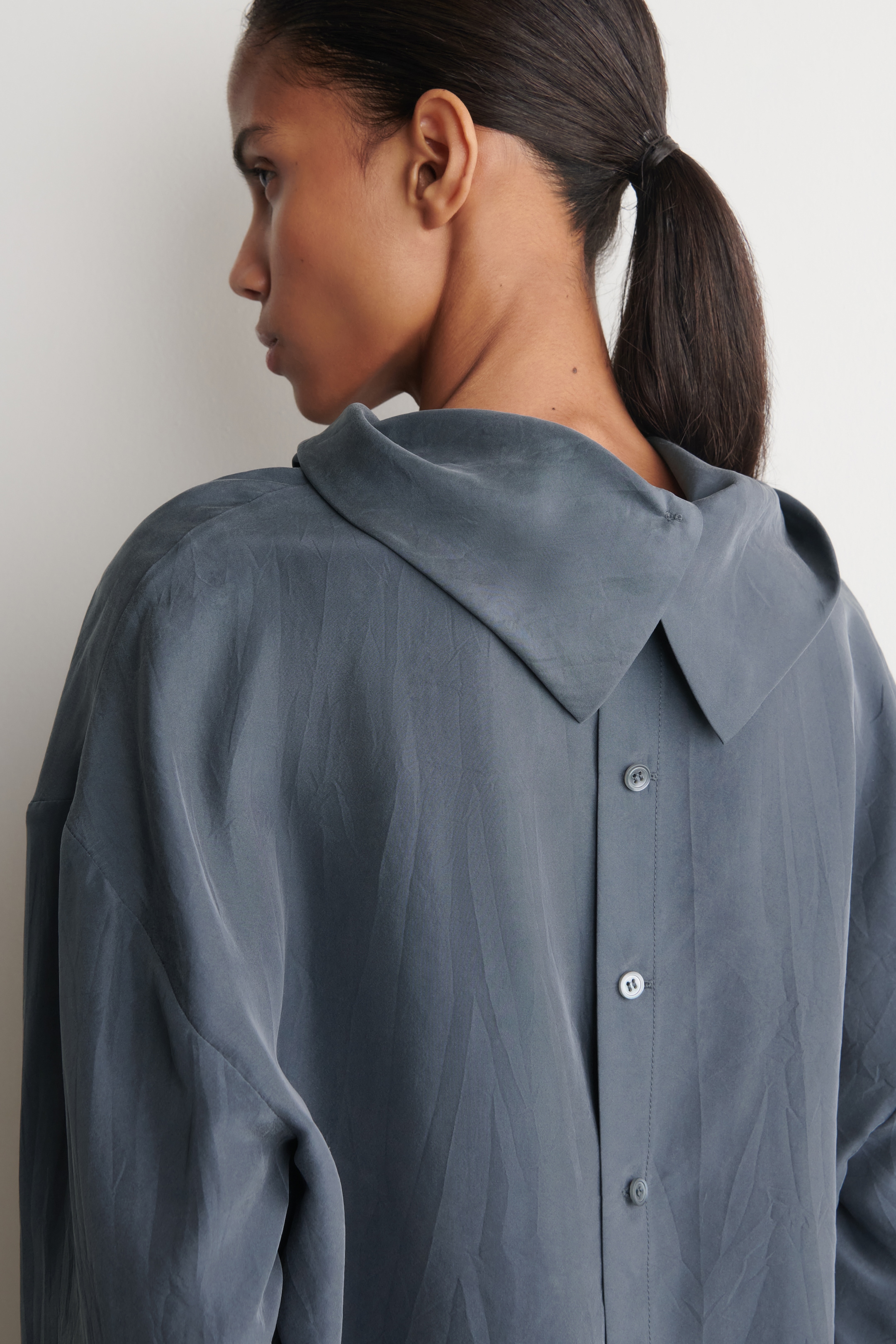 woman in navy silk top showing back detail