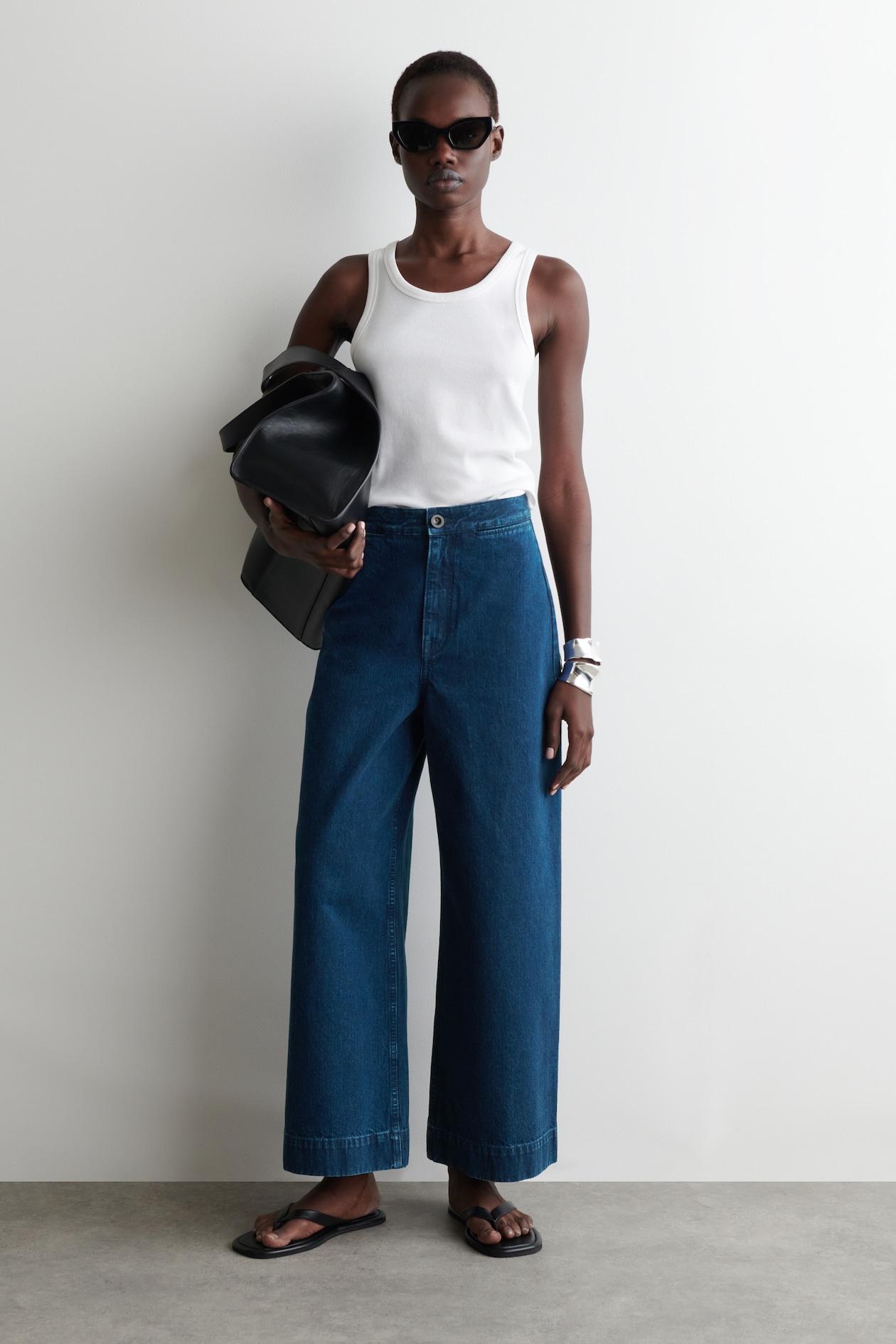 model wearing white vest and wide jeans