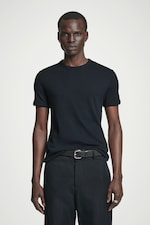 Placeholder for: Person wearing a fitted black t-shirt and black pants with a belt, standing against a plain white background.